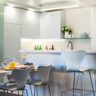 Small midcentury galley eat-in kitchen in New York with an undermount sink, flat-panel cabinets, grey cabinets, solid surface benchtops, white splashback, porcelain splashback, stainless steel appliances, porcelain floors and with island.