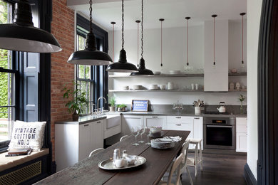 Urban dark wood floor eat-in kitchen photo in New York with a farmhouse sink, shaker cabinets, white cabinets, stainless steel appliances, no island and concrete countertops