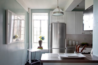 Foto de cocina actual con armarios estilo shaker, puertas de armario blancas, salpicadero amarillo, electrodomésticos de acero inoxidable y suelo de madera oscura