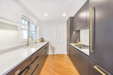 Medium sized urban galley enclosed kitchen in New York with a built-in sink, flat-panel cabinets, black cabinets, engineered stone countertops, stone slab splashback, no island, light hardwood flooring, stainless steel appliances and beige floors.