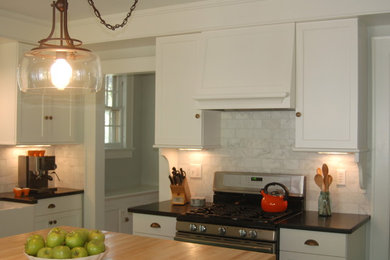 Enclosed kitchen - mid-sized traditional l-shaped painted wood floor enclosed kitchen idea in New York with a farmhouse sink, recessed-panel cabinets, white cabinets, granite countertops, white backsplash, subway tile backsplash, stainless steel appliances and an island