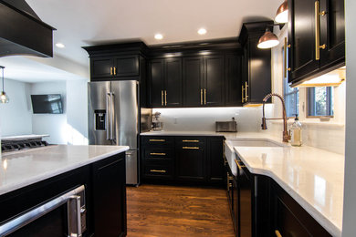 シカゴにある高級な中くらいなトラディショナルスタイルのおしゃれなキッチン (エプロンフロントシンク、落し込みパネル扉のキャビネット、黒いキャビネット、珪岩カウンター、白いキッチンパネル、サブウェイタイルのキッチンパネル、シルバーの調理設備、無垢フローリング、茶色い床、白いキッチンカウンター) の写真