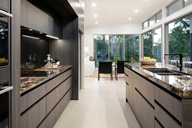Esempio di una cucina moderna di medie dimensioni con lavello sottopiano, ante lisce, ante in legno bruno, top in granito, paraspruzzi nero, paraspruzzi con lastra di vetro, elettrodomestici neri, pavimento in gres porcellanato, pavimento beige e top nero