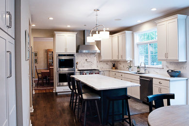 Eat-in kitchen - mid-sized traditional u-shaped dark wood floor eat-in kitchen idea in Philadelphia with an undermount sink, shaker cabinets, white cabinets, white backsplash, stone tile backsplash, stainless steel appliances and an island