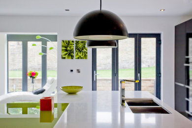Moderne Wohnküche mit Doppelwaschbecken, flächenbündigen Schrankfronten, schwarzen Schränken, Küchengeräten aus Edelstahl und zwei Kücheninseln in Sonstige