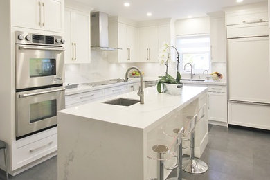 This is an example of a large modern l-shaped kitchen/diner in Montreal with a submerged sink, shaker cabinets, white cabinets, quartz worktops, white splashback, stone slab splashback, stainless steel appliances, ceramic flooring, an island, grey floors and white worktops.