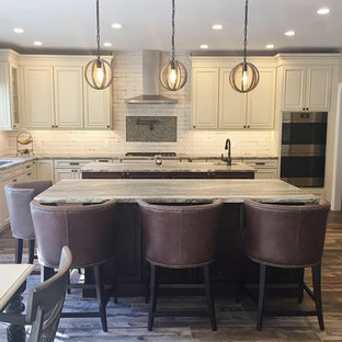 Large country l-shaped open plan kitchen in Philadelphia with an undermount sink, raised-panel cabinets, distressed cabinets, quartzite benchtops, white splashback, ceramic splashback, stainless steel appliances, porcelain floors, multiple islands, brown floor and multi-coloured benchtop.