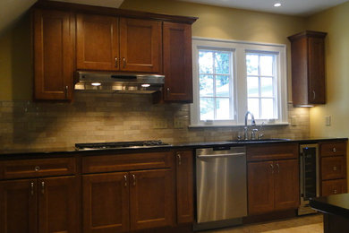 Example of a mid-sized arts and crafts galley kitchen design in Cincinnati with an undermount sink, shaker cabinets, dark wood cabinets, beige backsplash, stone tile backsplash and stainless steel appliances