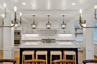 Eat-in kitchen - country l-shaped medium tone wood floor and brown floor eat-in kitchen idea in Houston with an undermount sink, shaker cabinets, white cabinets, quartzite countertops, white backsplash, subway tile backsplash, stainless steel appliances, an island and white countertops