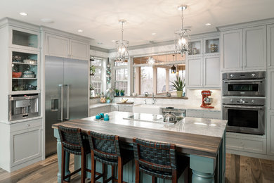 Imagen de cocina clásica con fregadero sobremueble, armarios estilo shaker, encimera de cuarzo compacto, electrodomésticos de acero inoxidable y una isla