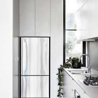 Design ideas for a mid-sized contemporary l-shaped kitchen in Melbourne with an undermount sink, flat-panel cabinets, white cabinets, grey splashback, stainless steel appliances, no island, beige floor and grey benchtop.