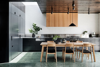 Inspiration för stora moderna linjära kök med öppen planlösning, med en dubbel diskho, släta luckor, svarta skåp, bänkskiva i rostfritt stål, stänkskydd i tegel, rostfria vitvaror, betonggolv och grönt golv