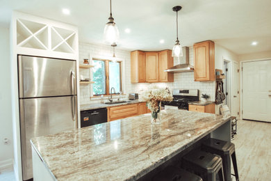 Example of a mid-sized cottage l-shaped laminate floor and gray floor eat-in kitchen design in Boston with an undermount sink, raised-panel cabinets, medium tone wood cabinets, granite countertops, white backsplash, porcelain backsplash, stainless steel appliances, an island and gray countertops