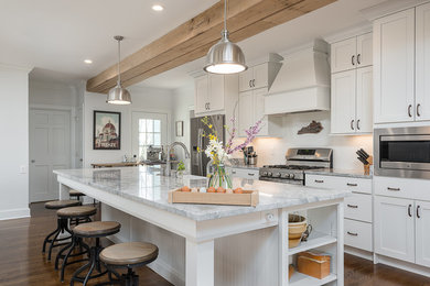 Mid-sized transitional galley medium tone wood floor and brown floor open concept kitchen photo in Other with shaker cabinets, white cabinets, white backsplash, stainless steel appliances, an island, a farmhouse sink, granite countertops and subway tile backsplash