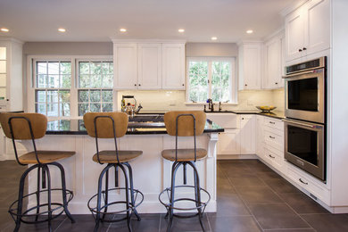Mid-sized country l-shaped porcelain tile eat-in kitchen photo in Philadelphia with a farmhouse sink, shaker cabinets, white cabinets, granite countertops, white backsplash, subway tile backsplash, stainless steel appliances and an island