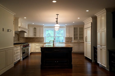 Inspiration for a large timeless u-shaped dark wood floor enclosed kitchen remodel in Philadelphia with an undermount sink, raised-panel cabinets, white cabinets, granite countertops, beige backsplash, ceramic backsplash, stainless steel appliances and an island