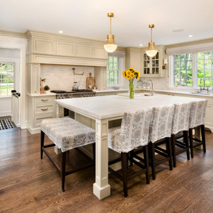 Photo of a traditional l-shaped eat-in kitchen in Philadelphia with an undermount sink, shaker cabinets, beige cabinets, white splashback, with island, brown floor, white benchtop, marble benchtops, marble splashback and medium hardwood floors.