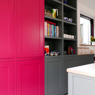 Large contemporary galley open plan kitchen in Essex with shaker cabinets, grey cabinets, laminate benchtops, orange splashback, ceramic splashback, stainless steel appliances, porcelain floors, with island, white floor and white benchtop.