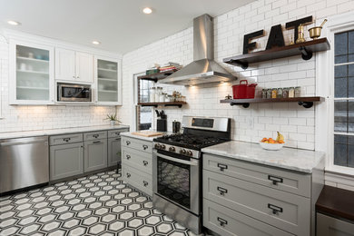 Example of a concrete floor kitchen design in Indianapolis with a farmhouse sink, shaker cabinets, marble countertops, white backsplash, subway tile backsplash and stainless steel appliances
