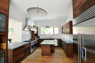 Example of a large trendy u-shaped dark wood floor and brown floor enclosed kitchen design in Chicago with an undermount sink, flat-panel cabinets, dark wood cabinets, soapstone countertops, white backsplash, subway tile backsplash and an island