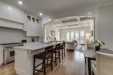 Example of a mid-sized transitional galley light wood floor eat-in kitchen design in Chicago with a drop-in sink, raised-panel cabinets, white cabinets, granite countertops, white backsplash, stone slab backsplash, stainless steel appliances and an island
