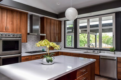 Mid-sized trendy u-shaped dark wood floor and brown floor kitchen photo in Orange County with an undermount sink, flat-panel cabinets, medium tone wood cabinets, solid surface countertops, white backsplash, ceramic backsplash, stainless steel appliances and an island