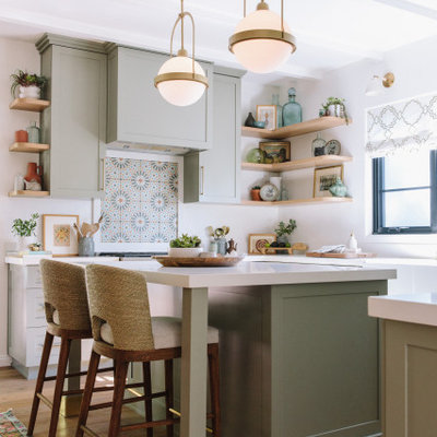 Example of a transitional u-shaped medium tone wood floor, brown floor and exposed beam kitchen design in Los Angeles with a farmhouse sink, shaker cabinets, green cabinets, quartz countertops, white backsplash, an island and white countertops