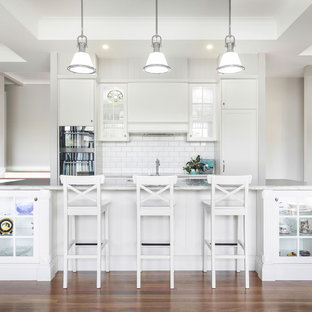 Inspiration for a transitional galley open plan kitchen in Brisbane with an undermount sink, shaker cabinets, white cabinets, white splashback, subway tile splashback, panelled appliances, dark hardwood floors, with island and white benchtop.