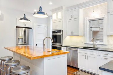 Kitchen - large transitional u-shaped medium tone wood floor and brown floor kitchen idea in Boston with an undermount sink, shaker cabinets, white cabinets, wood countertops, white backsplash, subway tile backsplash, stainless steel appliances, an island and brown countertops