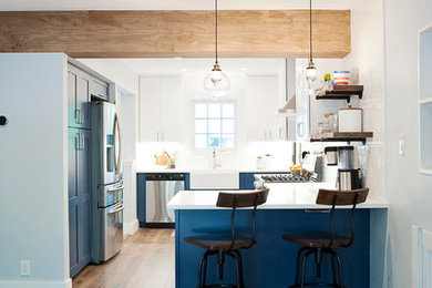 Inspiration for a mid-sized transitional vinyl floor and brown floor kitchen remodel in Austin with a farmhouse sink, shaker cabinets, blue cabinets, quartz countertops, white backsplash, ceramic backsplash, stainless steel appliances and white countertops