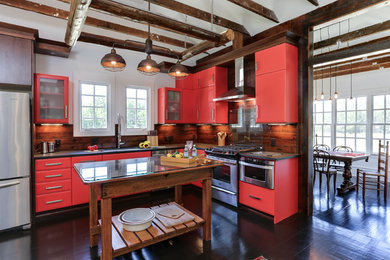 This is an example of a small farmhouse l-shaped open plan kitchen in Raleigh with a single-bowl sink, flat-panel cabinets, red cabinets, granite worktops, brown splashback, stainless steel appliances, dark hardwood flooring, an island, wood splashback and brown floors.