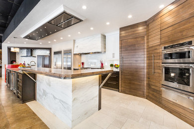 Eat-in kitchen - large contemporary u-shaped travertine floor eat-in kitchen idea in Albuquerque with an integrated sink, quartz countertops, white backsplash, stainless steel appliances, an island, glass sheet backsplash, shaker cabinets and dark wood cabinets