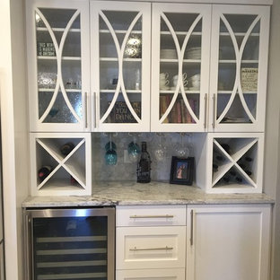 Exemple d'une grand cuisine américaine tendance en U avec un évier 3 bacs, un placard à porte shaker, des portes de placard blanches, un plan de travail en granite, une crédence grise, une crédence en carrelage de pierre, un électroménager en acier inoxydable, un sol en calcaire et un îlot central.