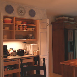 Réalisation d'une petit cuisine ouverte parallèle tradition avec un évier de ferme, un placard à porte vitrée, des portes de placard en bois brun, un plan de travail en bois, une crédence en bois, un électroménager encastrable, un sol en bois clair et une péninsule.
