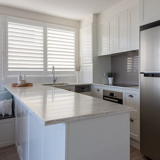 Offene, Mittelgroße Moderne Küche in U-Form mit Unterbauwaschbecken, Schrankfronten im Shaker-Stil, weißen Schränken, Mineralwerkstoff-Arbeitsplatte, Küchenrückwand in Metallic, Rückwand aus Spiegelfliesen, Küchengeräten aus Edelstahl, Linoleum, Halbinsel, buntem Boden und weißer Arbeitsplatte in Sunshine Coast