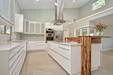 オースティンにある高級な中くらいなトランジショナルスタイルのおしゃれなキッチン (フラットパネル扉のキャビネット、白いキャビネット、クオーツストーンカウンター、アンダーカウンターシンク、白いキッチンパネル、石スラブのキッチンパネル、シルバーの調理設備、コンクリートの床) の写真
