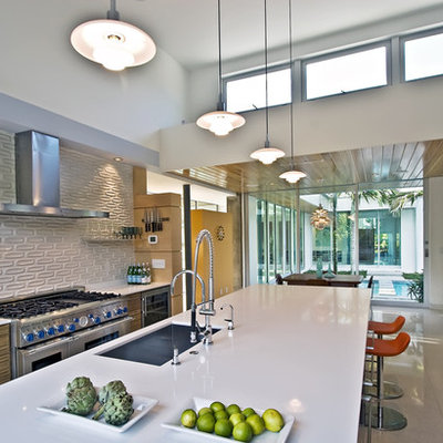 Example of a minimalist galley eat-in kitchen design in Miami with an undermount sink, flat-panel cabinets, light wood cabinets, quartz countertops, white backsplash, subway tile backsplash and stainless steel appliances