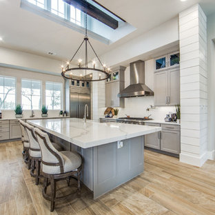 Inspiration for a large country eat-in kitchen in Austin with a farmhouse sink, shaker cabinets, grey cabinets, quartz benchtops, white splashback, ceramic splashback, stainless steel appliances, porcelain floors, multiple islands and beige floor.