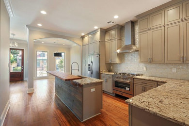 Photo of a large traditional single-wall enclosed kitchen in New Orleans with a submerged sink, louvered cabinets, beige cabinets, granite worktops, beige splashback, brick splashback, stainless steel appliances, medium hardwood flooring, an island and brown floors.