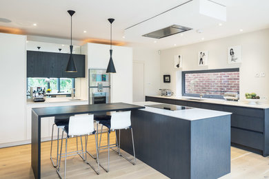 Moderne Küche mit flächenbündigen Schrankfronten, hellem Holzboden und Kücheninsel in London