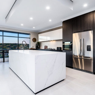 Photo of a large contemporary galley kitchen in Perth with an undermount sink, flat-panel cabinets, black cabinets, white splashback, stainless steel appliances, with island, white floor and black benchtop.