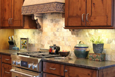 Eat-in kitchen - large rustic galley slate floor eat-in kitchen idea in Milwaukee with a farmhouse sink, recessed-panel cabinets, medium tone wood cabinets, granite countertops, multicolored backsplash, stone tile backsplash, stainless steel appliances and an island