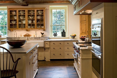 Photo of a medium sized rural l-shaped kitchen/diner in Burlington with a belfast sink, flat-panel cabinets, white cabinets, granite worktops, stainless steel appliances, dark hardwood flooring, brown floors and grey worktops.