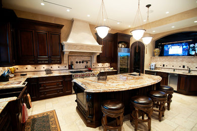 Eat-in kitchen - large mediterranean l-shaped travertine floor eat-in kitchen idea in Vancouver with an undermount sink, raised-panel cabinets, dark wood cabinets, granite countertops, beige backsplash, stainless steel appliances and an island