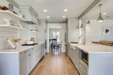 Design ideas for a medium sized country kitchen in Austin with a belfast sink, shaker cabinets, engineered stone countertops, light hardwood flooring and white worktops.