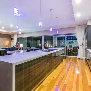 Large contemporary galley eat-in kitchen in Perth with a drop-in sink, flat-panel cabinets, dark wood cabinets, quartz benchtops, metallic splashback, glass sheet splashback, stainless steel appliances, medium hardwood floors and with island.