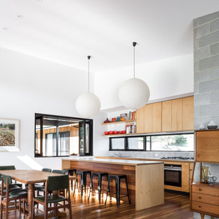 Contemporary galley open plan kitchen in Other with flat-panel cabinets, medium wood cabinets, black appliances, dark hardwood floors, with island and brown floor.