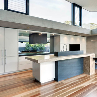 Design ideas for an expansive modern l-shaped eat-in kitchen in Sydney with an undermount sink, flat-panel cabinets, beige cabinets, marble benchtops, grey splashback, glass sheet splashback, medium hardwood floors and with island.