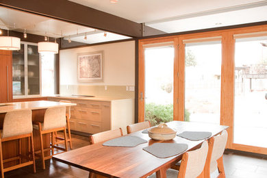 Ejemplo de cocina comedor minimalista con armarios con paneles lisos, puertas de armario de madera clara y salpicadero beige