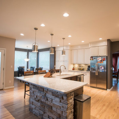Large eclectic single-wall light wood floor and beige floor open concept kitchen photo in Denver with an undermount sink, raised-panel cabinets, white cabinets, quartz countertops, beige backsplash, glass tile backsplash, stainless steel appliances and an island